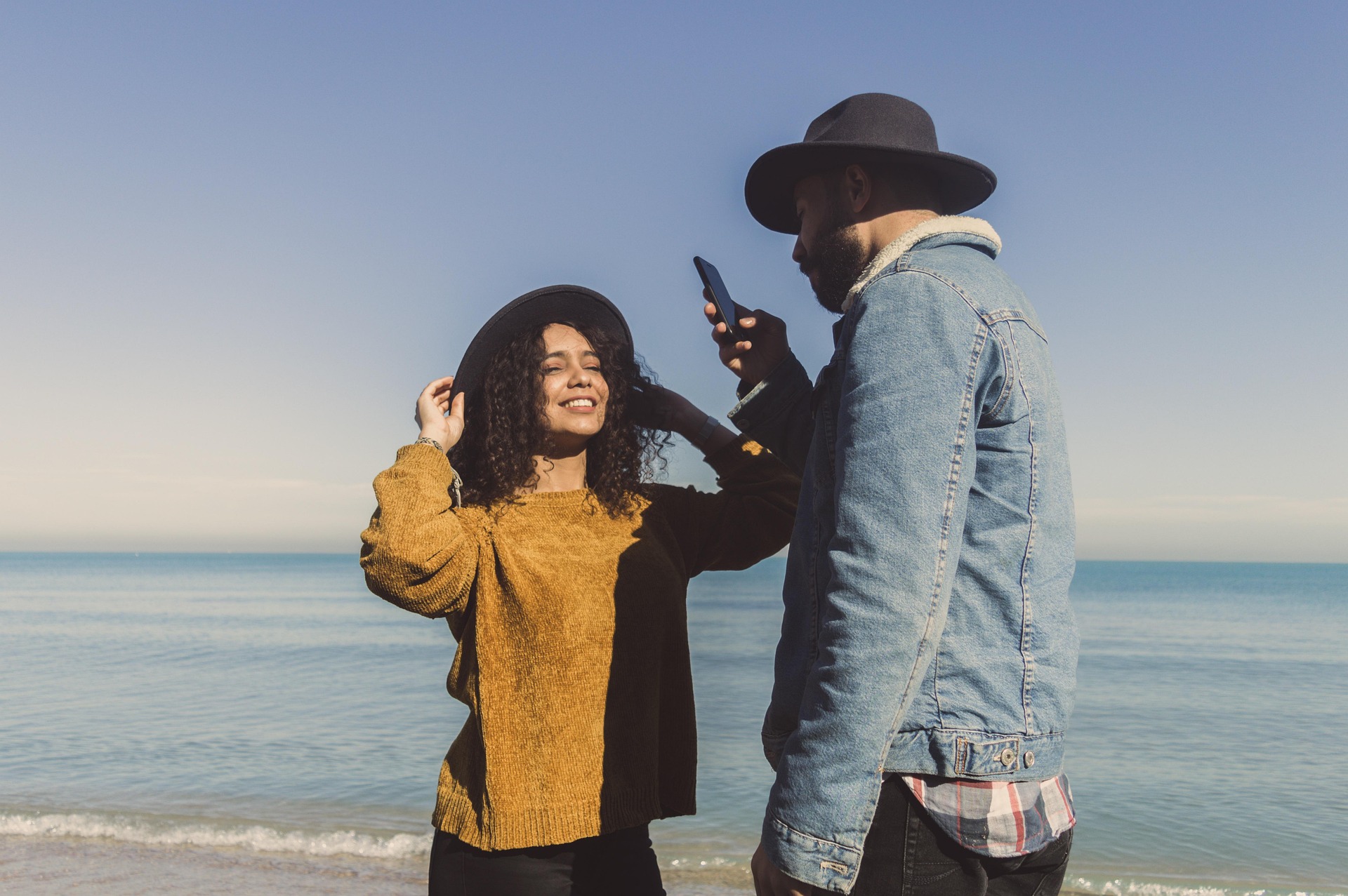 A couple near the water wearing hats smiling